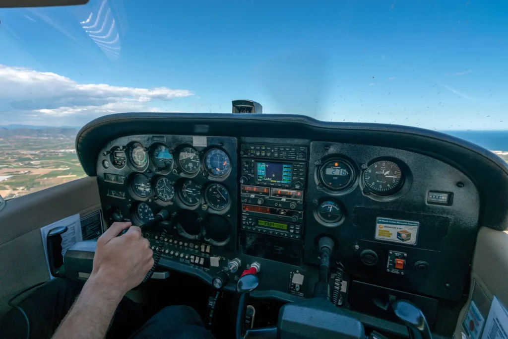 View from inside a small aircraft cockpit during VFR flight, showing flight instruments and pilot controls.